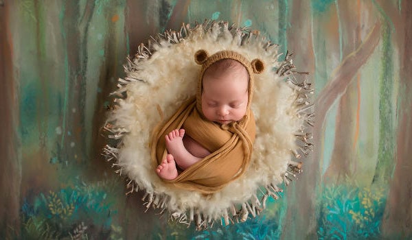 A sleeping baby dressed as a bear for a photography shoot