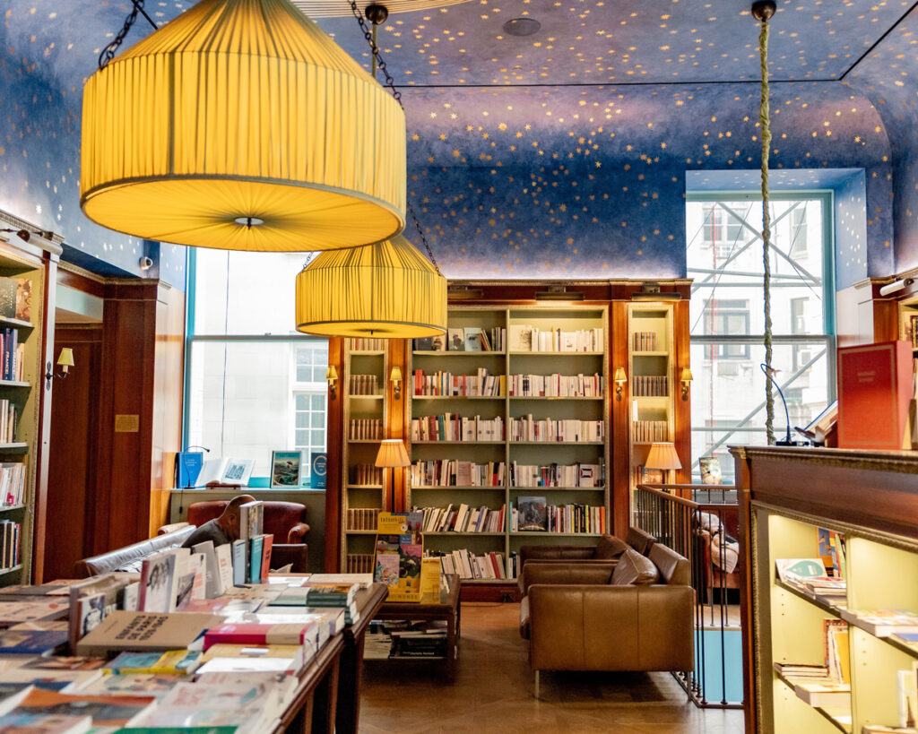 A bookstore reading room with low hanging lights and starry ceiling